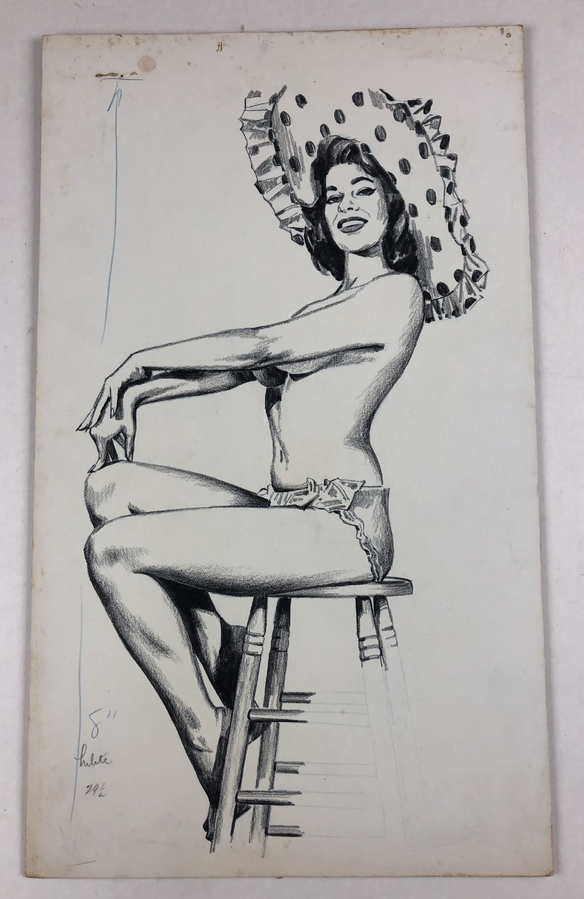 topless woman seated on stool wearing large hat with polka dots
