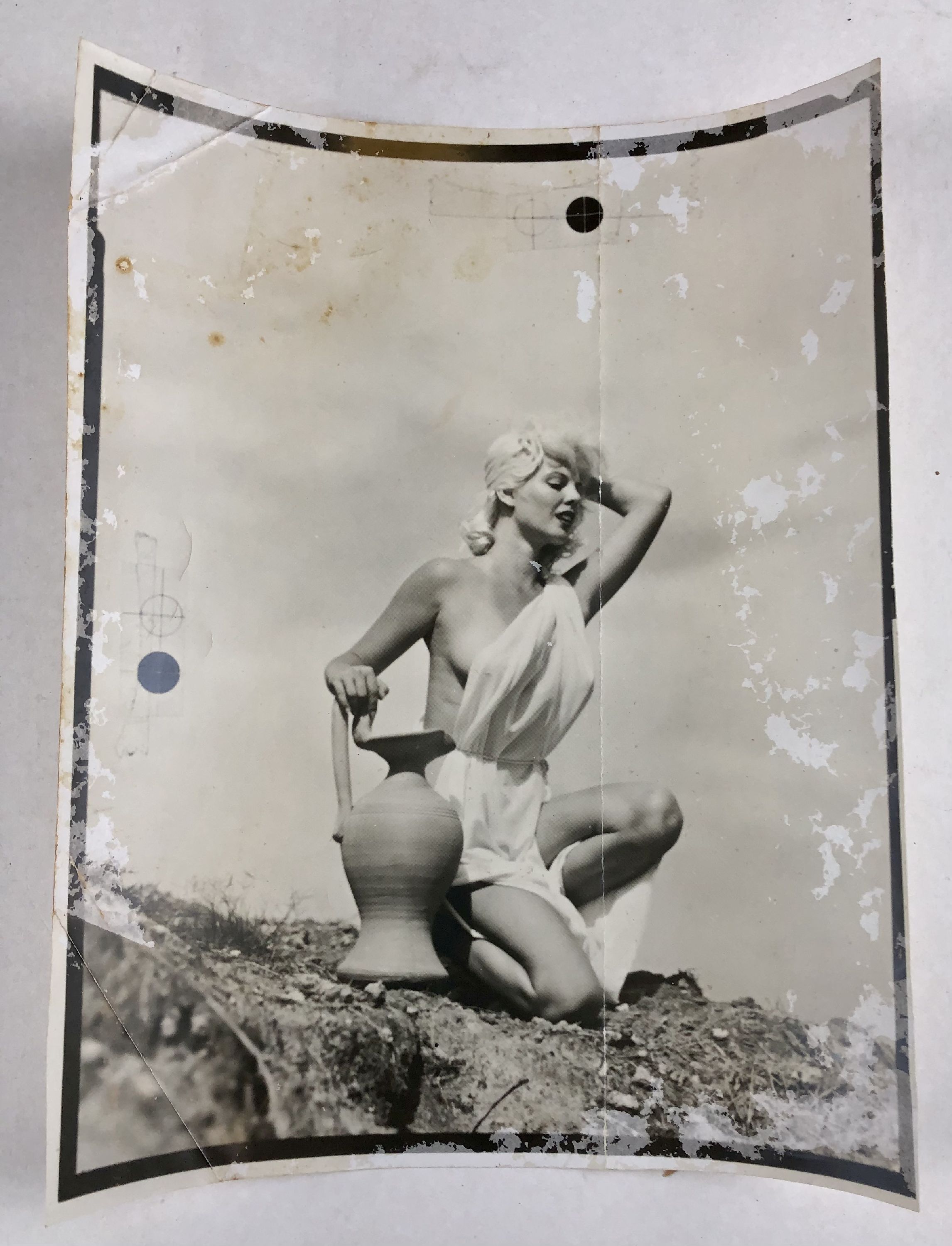 black and white photograph that was basis for paintings of blonde woman in toga kneeling next to clay vase