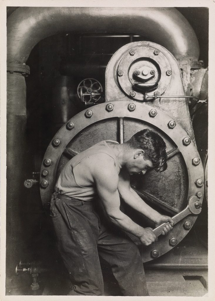 Black and white photograph of a man tightening a bold by Lewis Hine.