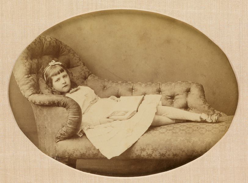 sepia portrait of a little girl reading on a couch