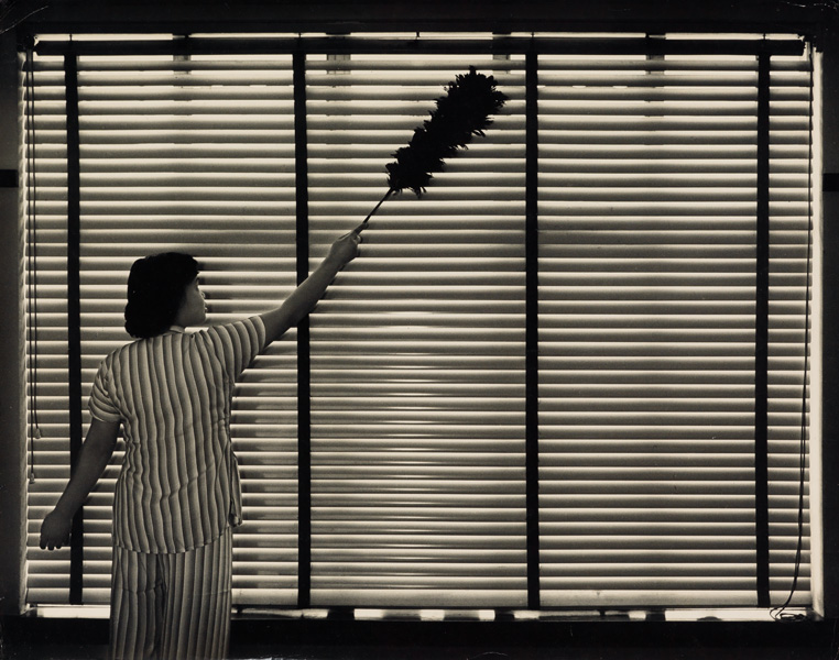 monochrome portrait of a woman cleaning window blinds