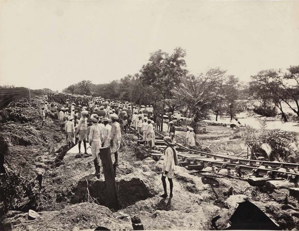 Image of Indian people walking along a train track. 