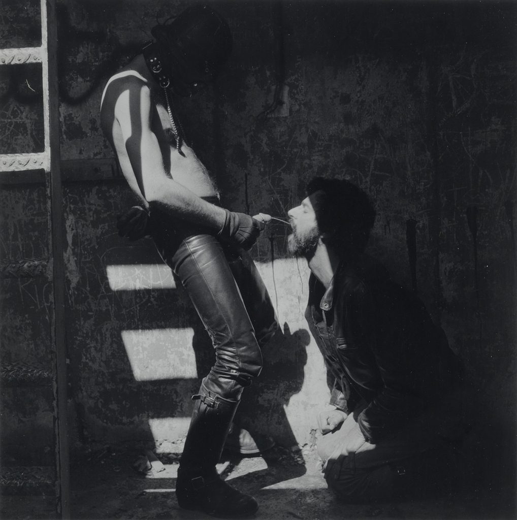 Black and white photograph of a man peeing into another man's mouth by Roberth Mapplethorpe.