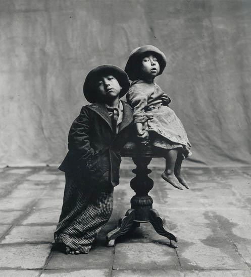 Irving Penn, Cuzco Children, Cuzco, black and white silver print of a little boy and girl with the little girl sitting on a table, 1948.